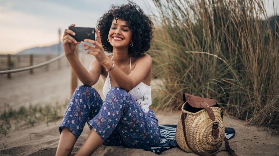 
		Lachende Frau fotografiert mit Handy im Urlaub
	